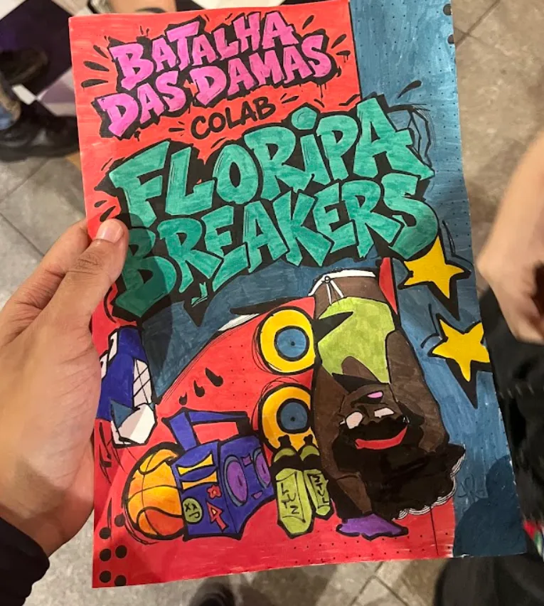 Cartaz desenhado à mão com os dizeres “Batalha das Damas colab Floripa Breakers”, uma b-girl de ponta-cabeça, caixas de som, um rádio e uma bola de basquete.